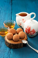 Obraz na płótnie Canvas Homemade sweets in cocoa powder on oak board with tea and teapot