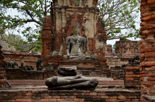 Broken buddha statue and ancient building