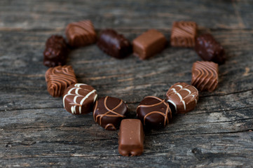 Different types of chocolate candies on a wooden background