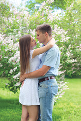 Beautiful young loving couple hugging in blooming spring garden