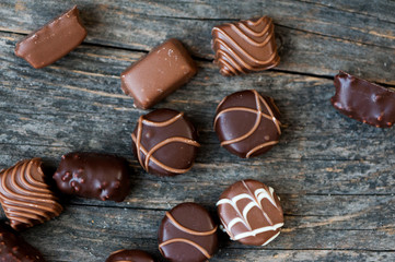 Different types of chocolate candies on a wooden background