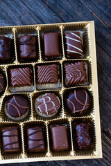 Different types of chocolate candies on a wooden background