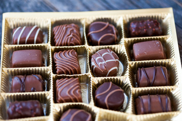 Different types of chocolate candies on a wooden background
