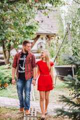 Young man and woman on the nature. Playful couple in love. Woman if red dress. Man in red shirt