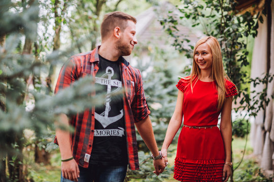 Young man and woman on the nature. Playful couple in love. Woman if red dress. Man in red shirt