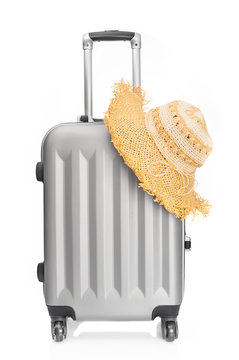 Travel luggage and straw hat on white background