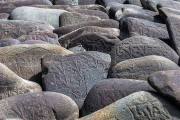 Carved Buddhist Mani Stones near Thiksay Monastery, Leh, Ladakh. Mani stones are rocks inscribed with the six syllabled mantra of Avalokiteshvara, as a form of prayer in Tibetan Buddhism.