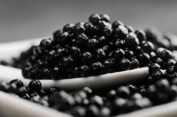 spoon of black caviar close-up in a white bowl side view