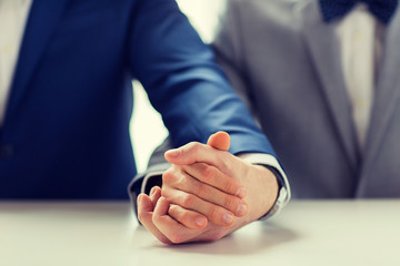 close up of happy male gay couple holding hands