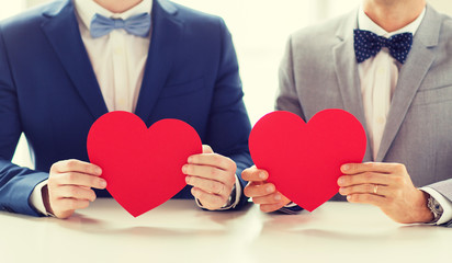 close up of male gay couple holding red hearts