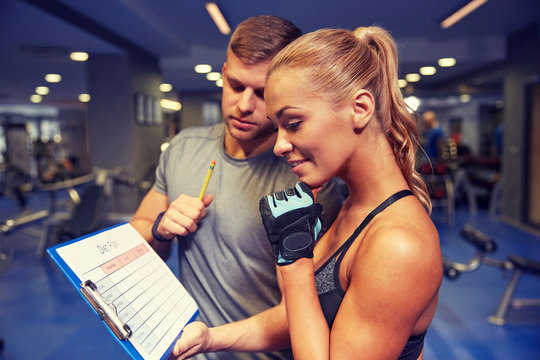 smiling woman with trainer and clipboard in gym