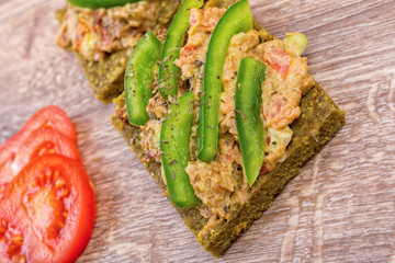 Raw bread with a spread decorated with pepper and tomatoes