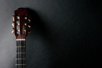 Neck of an old acoustic guitar on a black background (with copy space for your text) - obrazy, fototapety, plakaty