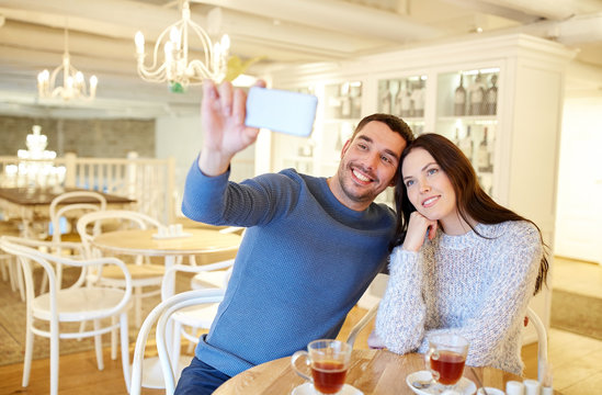 couple taking smartphone selfie at cafe restaurant