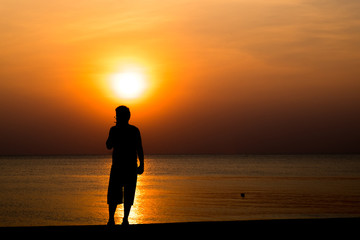 man smoking and sunset silhouette at the beach