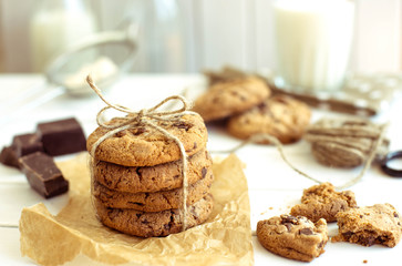 Freshly baked chocolate chip cookies with glass of milk on rustic wooden table. The toning.