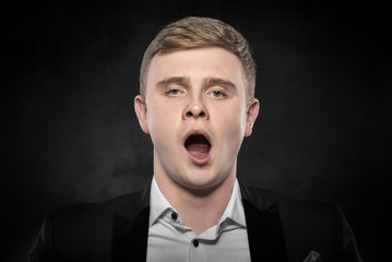 Businessman in black suit yawning. 