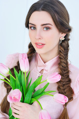 Beautiful young woman holding a bunch of delicate spring pink tulips in front of her