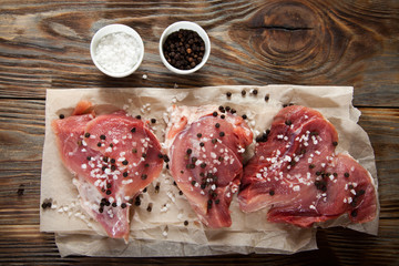 Top view raw pork chop steak and garlic, pepper on wooden background.