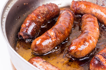 Homemade sausages frying in fat