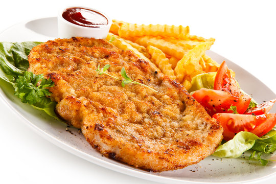 Fried pork chop, French fries and vegetables