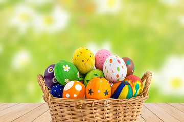 Colorful Easter eggs in a basket on wood texture on green flower