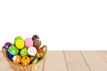 Colorful Easter eggs in a basket on wood texture isolated on whi