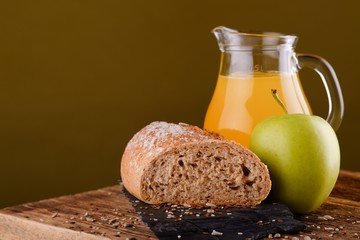 Loaf of bread on black stone with apple and juice