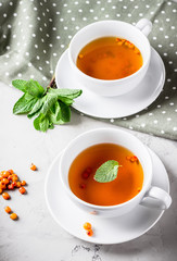 Two cups of tea with mint and berries.