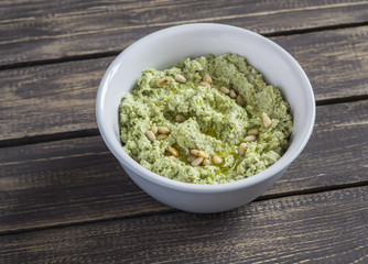 Delicious vegetarian broccoli and pine nuts hummus on wooden background. Healthy food