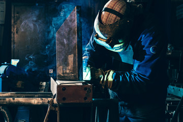 Welder in his workplace welding metal - obrazy, fototapety, plakaty