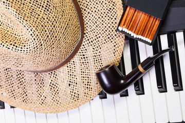 Piano keyboard,straw hat  and luxury pipe