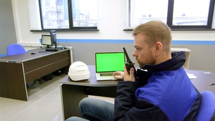 engineer looks at the green screen and talking on walkie-talkie inside the control room - Powered by Adobe