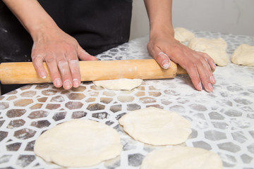Obraz na płótnie Canvas sheeting the dough with a rolling pin in the kitchen