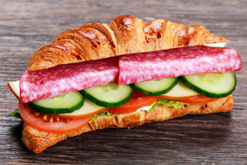 Fresh croissant with salami, chesse and vegetables