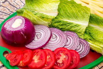 Hamburgers with fresh sliced vegtables and fries.