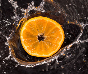 Fototapeta na wymiar Orange in water splashes on a black background