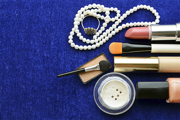 Set of women's cosmetics, pearl necklace and ring  on blue background. Beauty accessories.