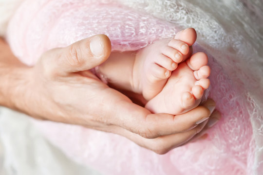 Baby feet in father hands. Tiny Newborn Baby's feet on male shap