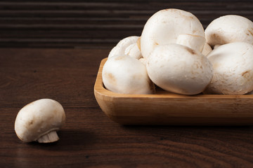 Fresh raw porcini boletus mushrooms in square bamboo bowl. Wood background