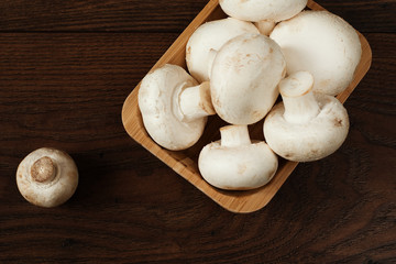 Fresh raw porcini boletus mushrooms in square bamboo bowl. Wood background.