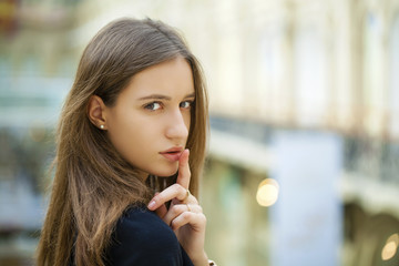 Portrait of attractive young haired woman with finger on lips