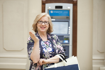 An elderly woman with shopping blonde is on the background in sh