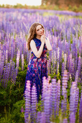 girl with flowers lupines in a field at sunset