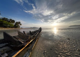 Fototapeta na wymiar Broken fishermens boat on the tropical sunset background