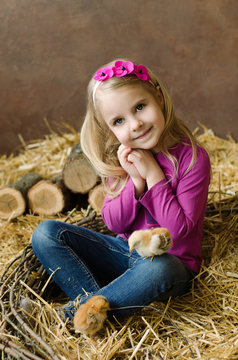 little blond-hair smiling girl with a chicken in the nest