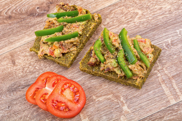 Raw bread with a spread decorated with pepper and tomatoes