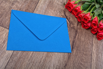 Blue envelope and roses on a wooden background