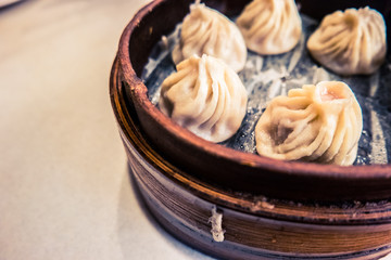 Traditional chinese food, steamed dumpling served on table in a wooden dish and with wooden chopsticks.