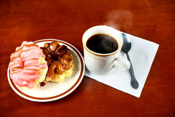 Two delicious sugared ring donuts served on white plate with a cup of hot drink 